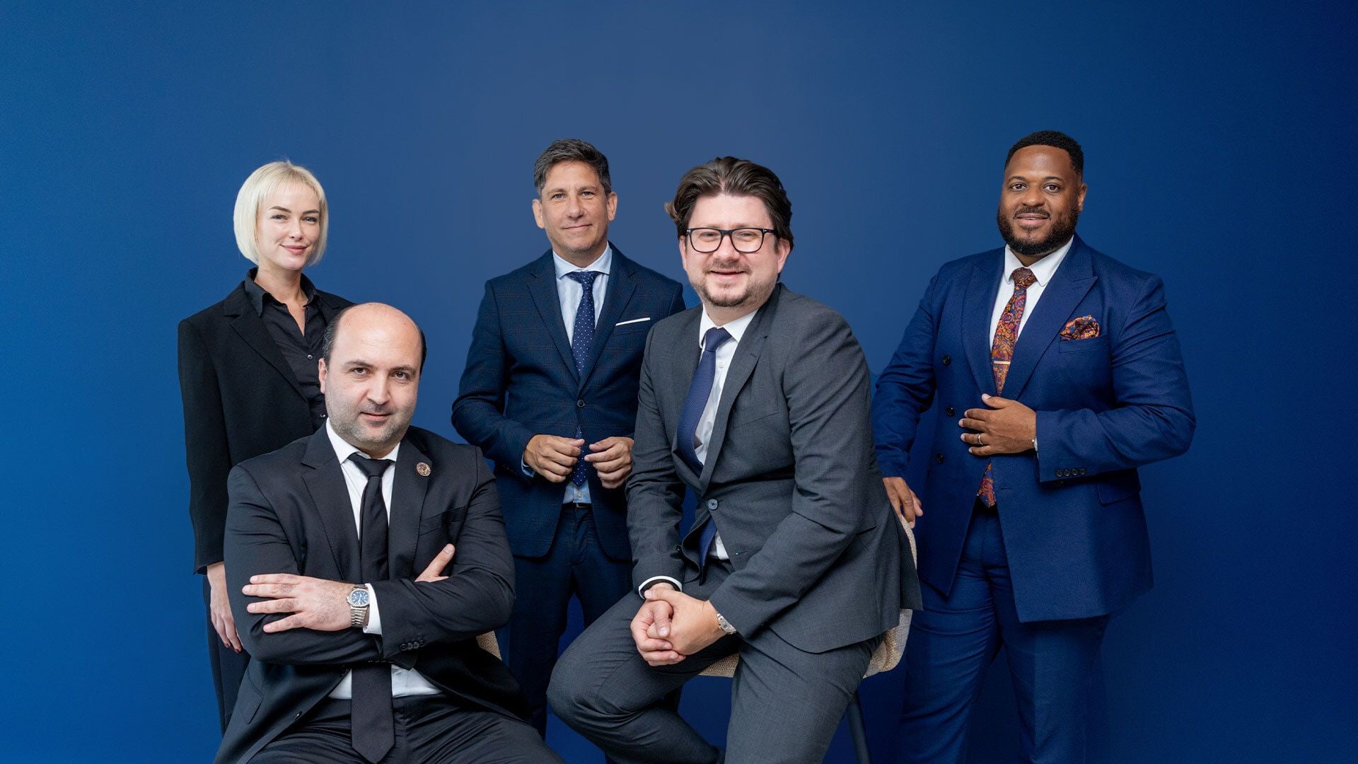 Six Professionals on Office Bench in Business Attire A group of six people sitting on a bench in a modern office, dressed in business attire. They appear professional and confident, with a calm demeanor.